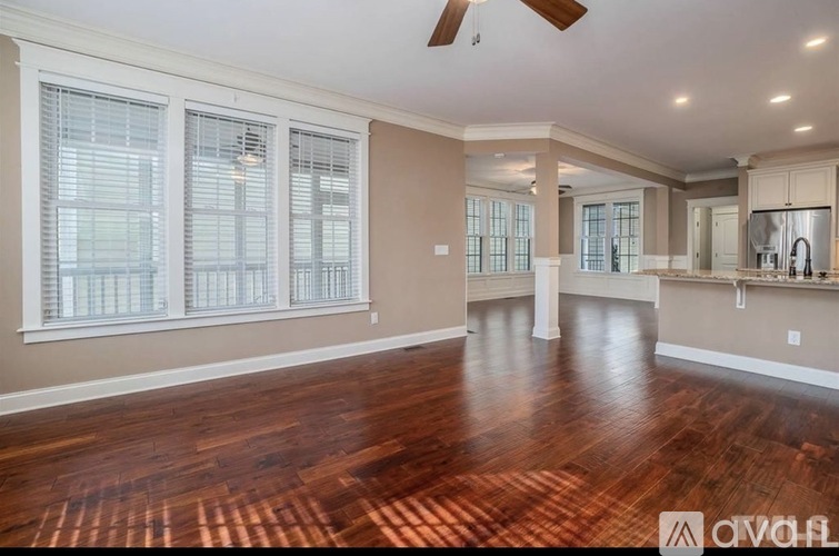 A spacious room with wood flooring and a ceiling fan.
