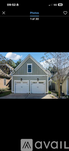 A house with a grey roof and two white garage doors.