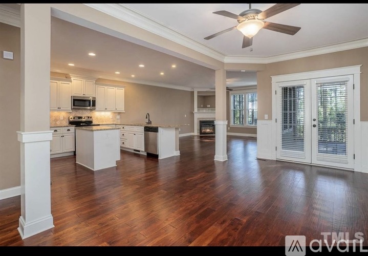 A spacious kitchen with wooden floors and white cabinets.