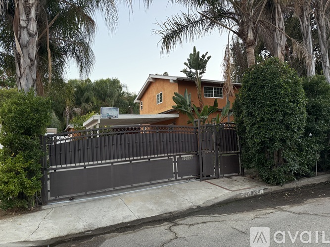 A house with a gate and a tree in front of it.