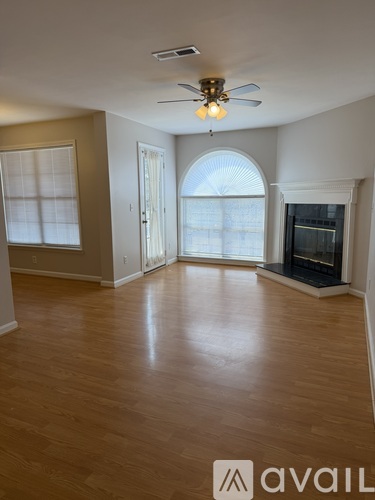 A spacious living room with a fireplace and a ceiling fan.