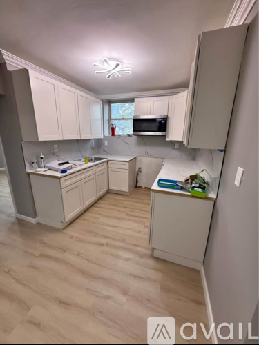 A kitchen with white cabinets and a wooden floor.