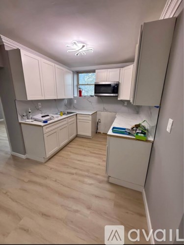 A kitchen with white cabinets and a wooden floor.
