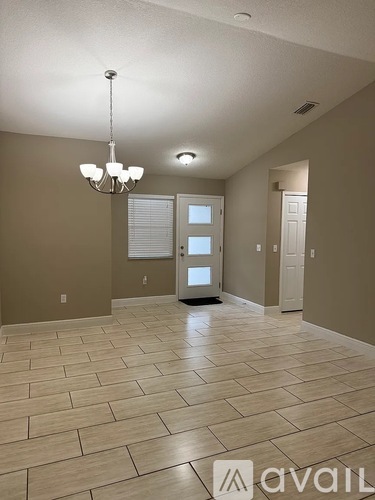A spacious room with a chandelier and tiled flooring.