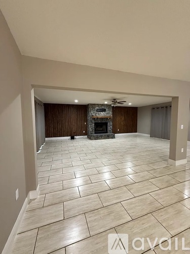 A spacious living room with a fireplace and tiled flooring.