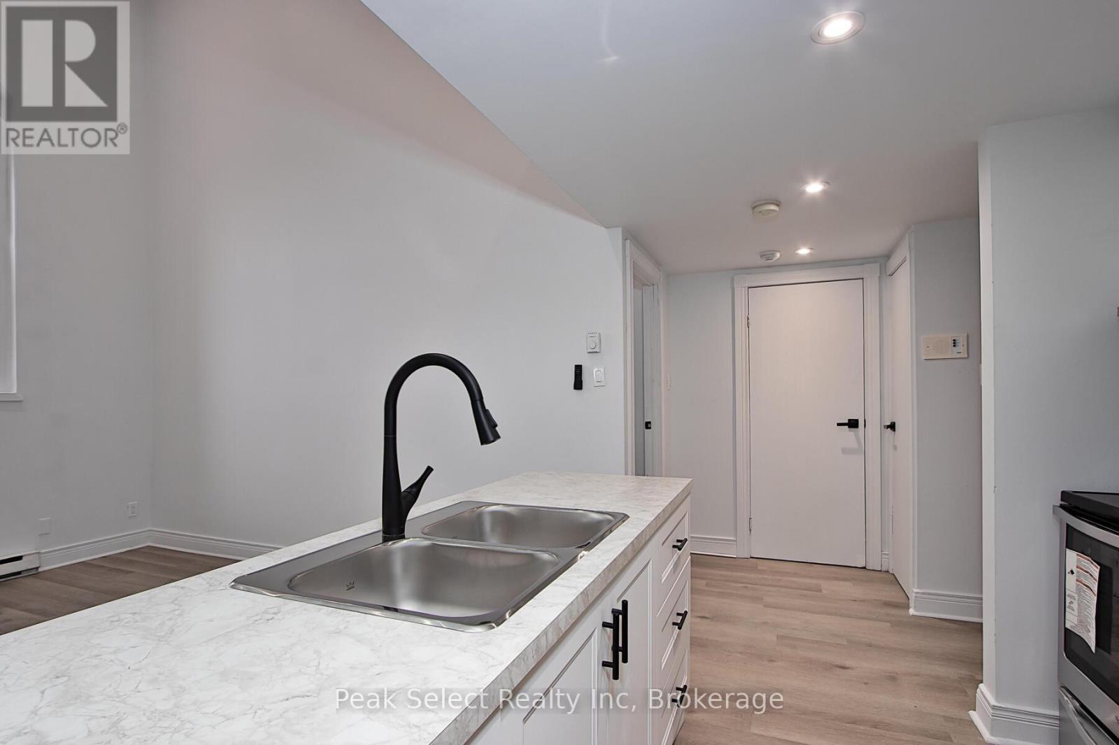 A kitchen with a sink and a black faucet.