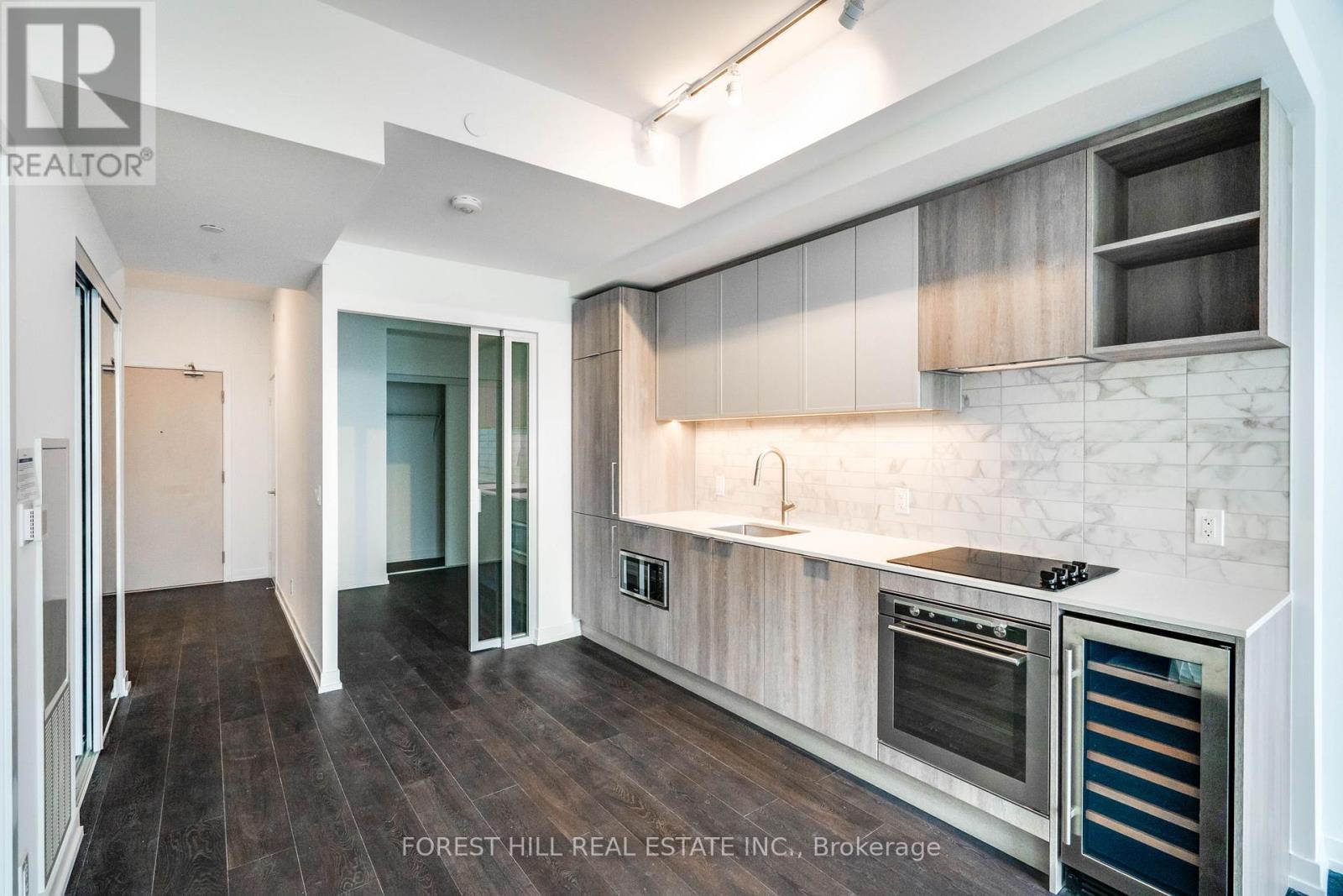 A modern kitchen with dark wood floors and stainless steel appliances.
