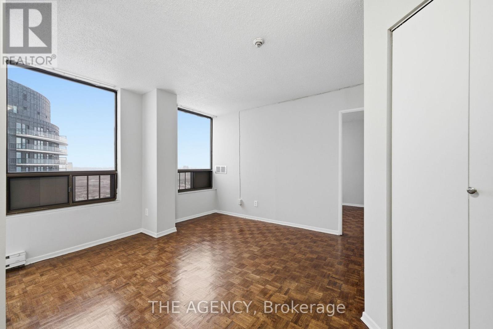 A room with a wooden floor and white walls, with a large window and a door.