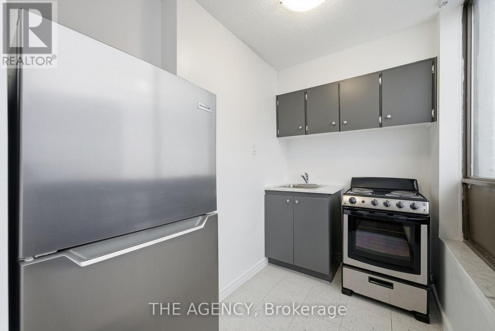 A small kitchen with a refrigerator, oven, and cabinets.