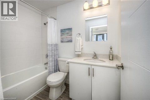 A white bathroom with a toilet, sink, and shower.