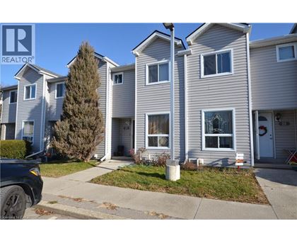A realtor photo of a grey house with a white door and windows.