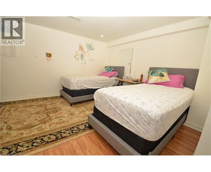 A bedroom with two beds and a rug on the floor.