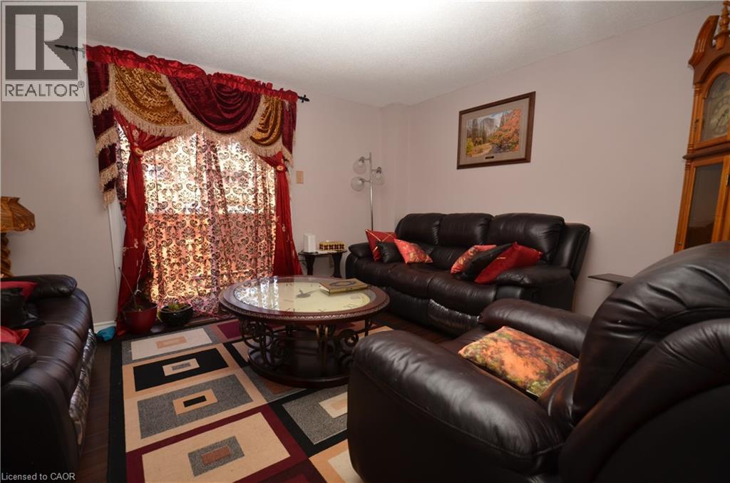 A living room with a black leather couch and a round table with a glass top.