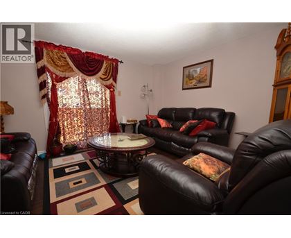 A living room with a black leather couch and a round table with a glass top.