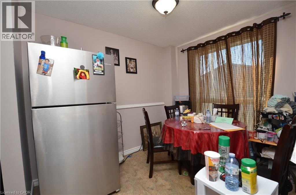 A kitchen with a refrigerator, table, and chairs.
