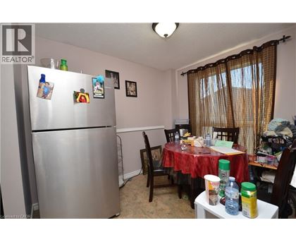 A kitchen with a refrigerator, table, and chairs.