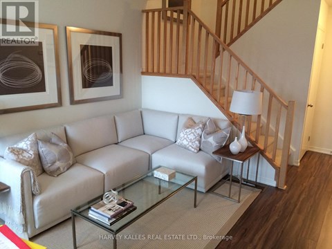 A living room with a white couch and a glass coffee table.