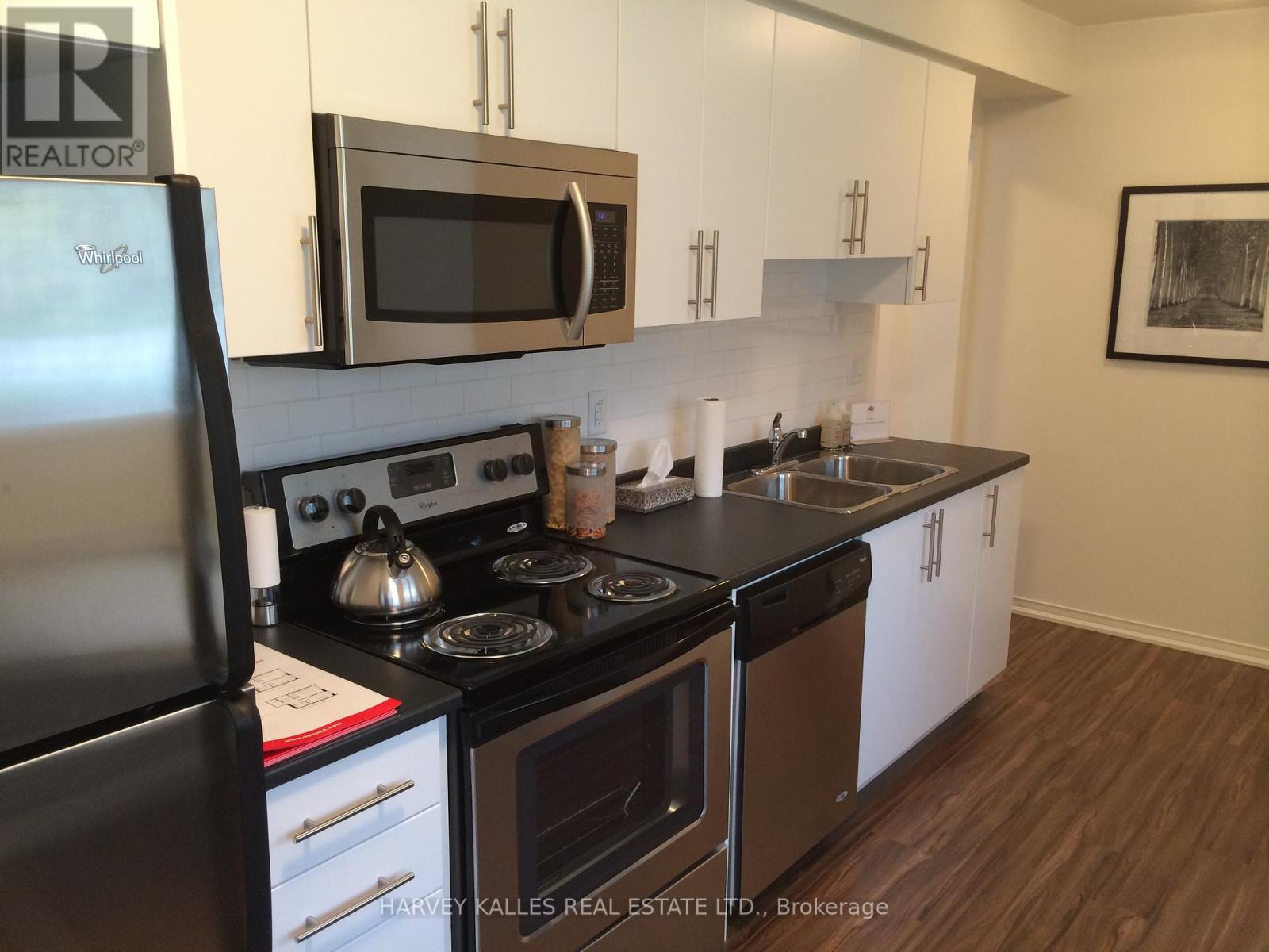 A kitchen with a black fridge and stove top oven.