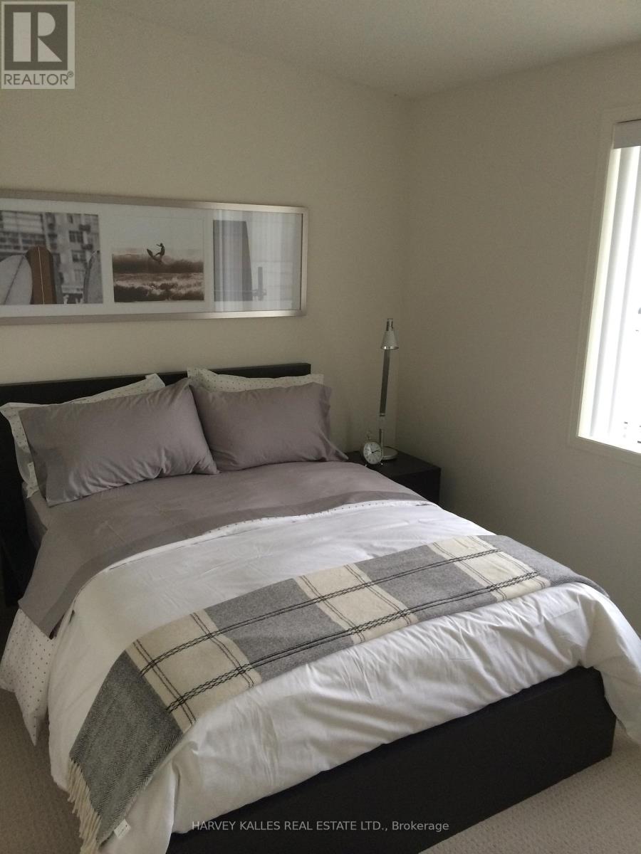A bedroom with a bed covered in a plaid comforter.