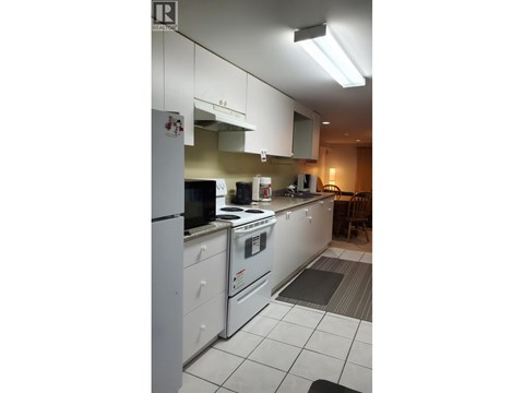 A kitchen with white appliances and cabinets.