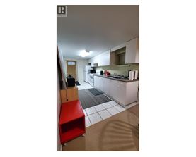A kitchen with a red stool and white cabinets.