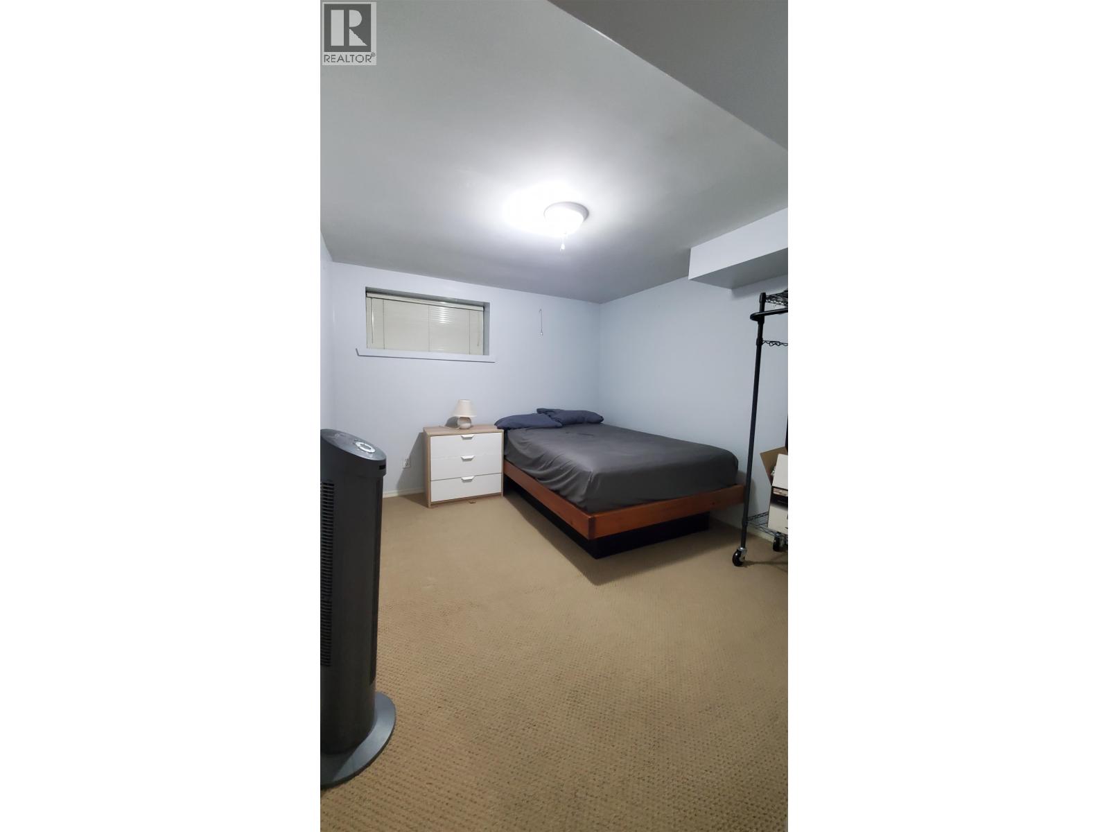 A bedroom with a bed, nightstand, and speaker.