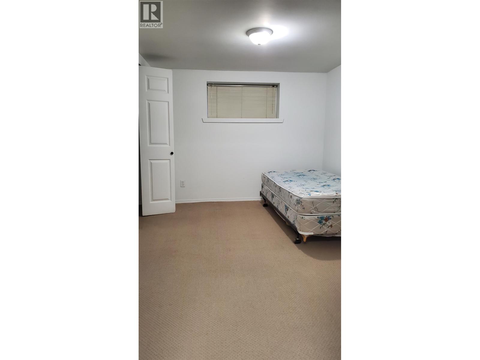 A bedroom with a bed, a door, and a window.