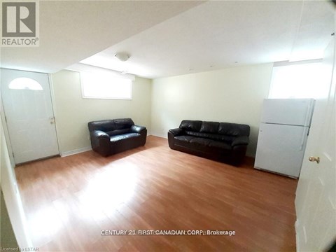 A living room with two black leather sofas and a wooden floor.