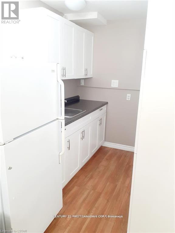 A kitchen with white cabinets and a fridge.