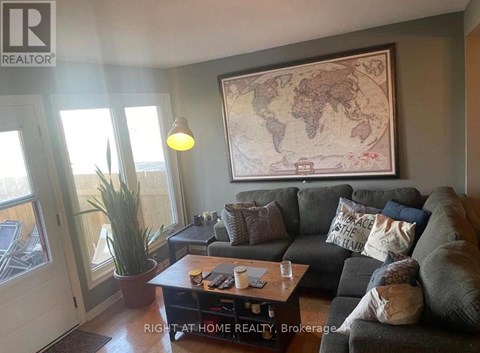 A living room with a grey couch, a world map on the wall, and a coffee table with a plant on it.