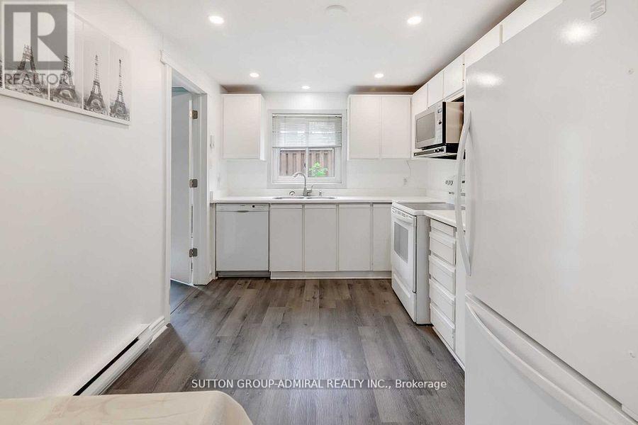 A kitchen with white cabinets and a wooden floor.