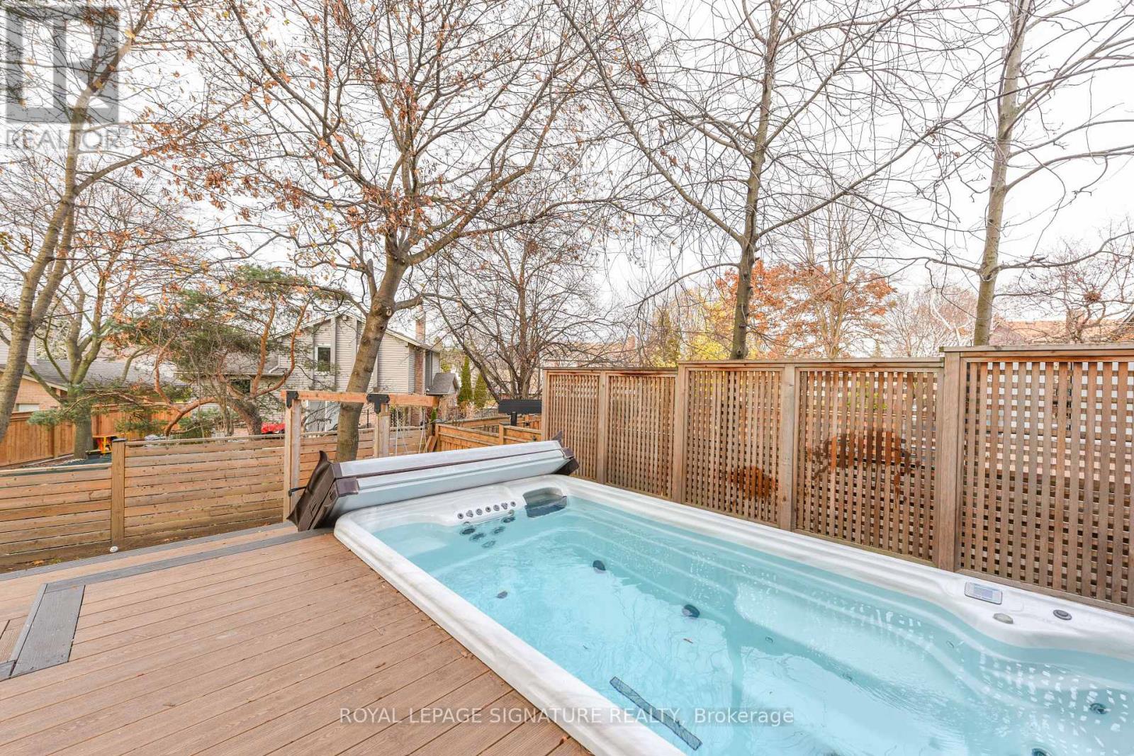 A hot tub sits on a wooden deck surrounded by a fence.