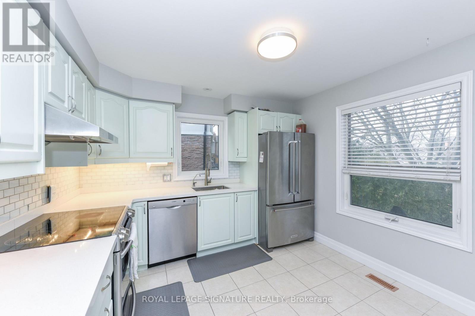 A kitchen with white cabinets and a stainless steel refrigerator.