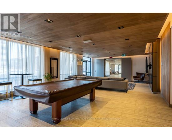 A well-lit room with a pool table and a couch.