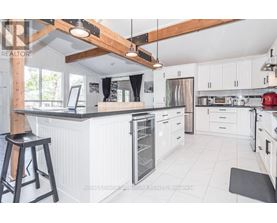 A kitchen with white cabinets and a black stool.