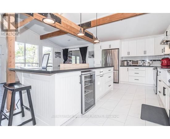 A kitchen with white cabinets and a black stool.