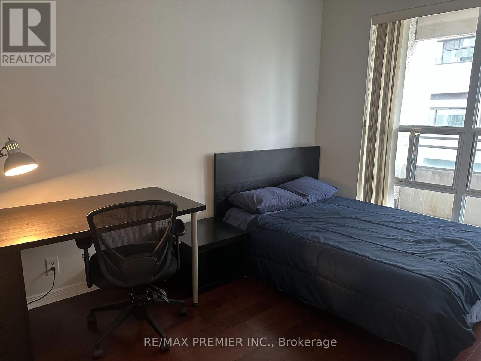 A bedroom with a bed, desk, and chair.