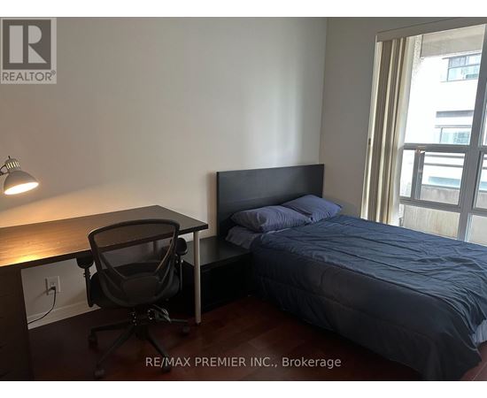 A bedroom with a bed, desk, and chair.