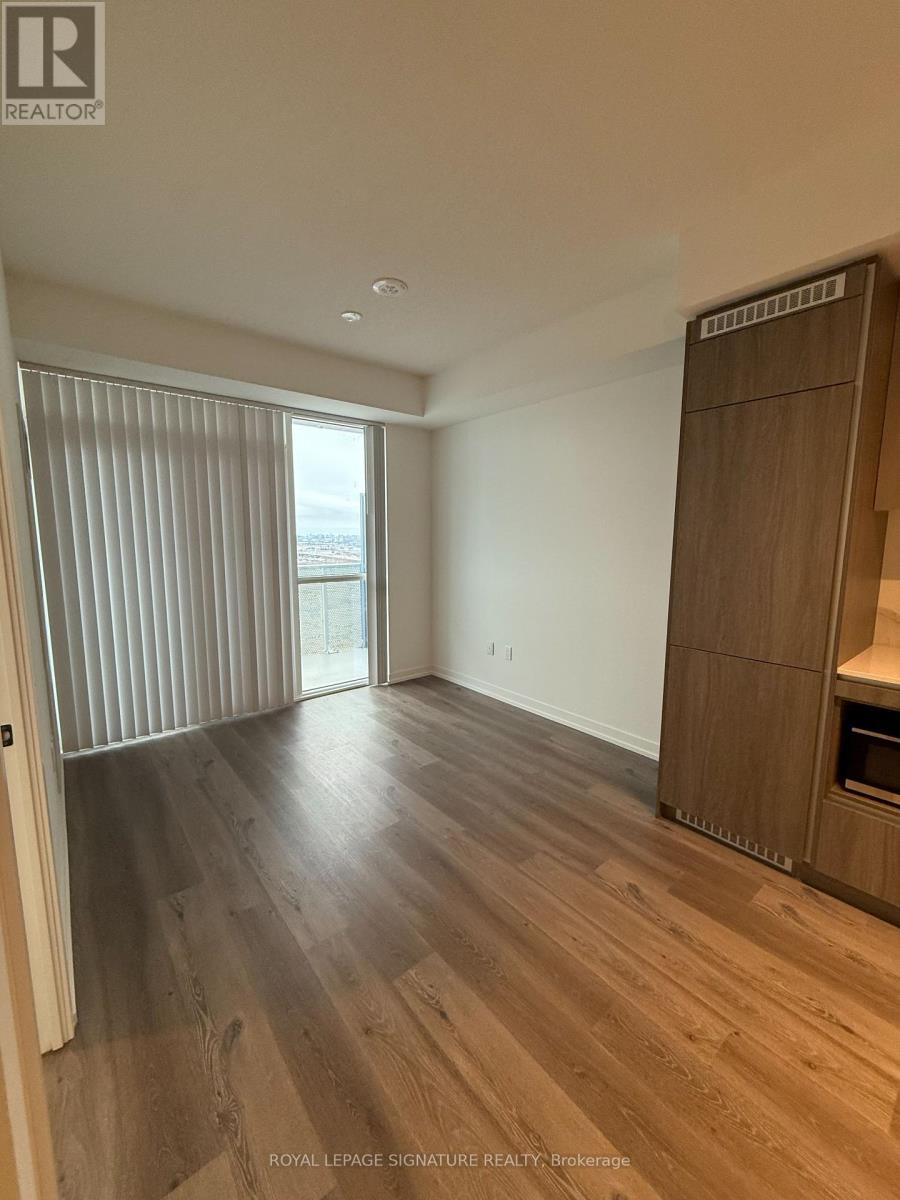 A room with wooden flooring and a large window with blinds.