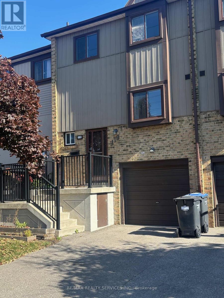 A residential building with a black trash bin in front of it.