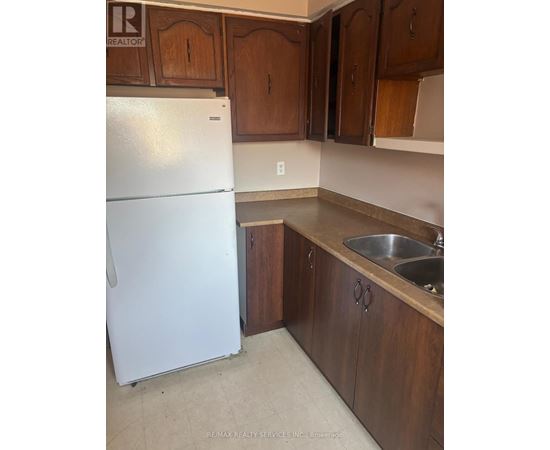 A white refrigerator in a kitchen with wooden cabinets.