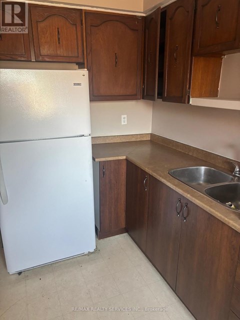 A white refrigerator in a kitchen with wooden cabinets.