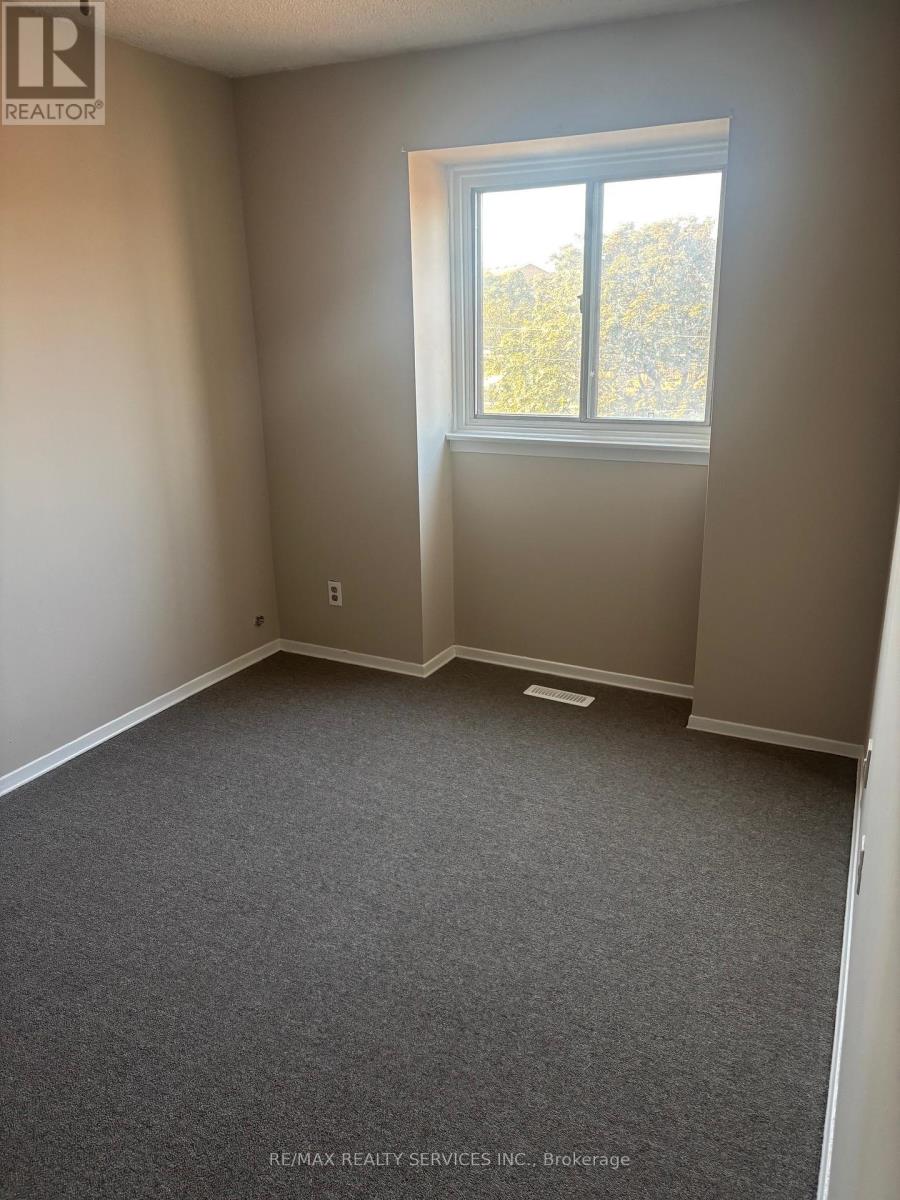 A room with a window and a grey carpet.