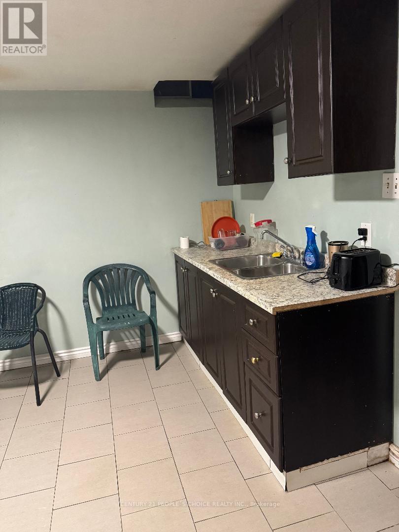 A kitchen with a black refrigerator, a sink, and two chairs.
