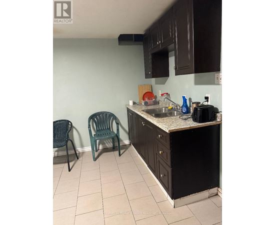 A kitchen with a black refrigerator, a sink, and two chairs.