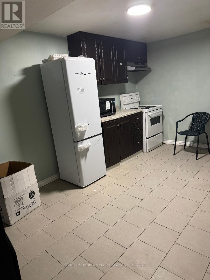 A kitchen with a white refrigerator, a white stove, and a black chair.