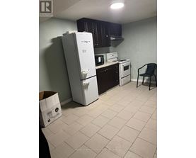 A kitchen with a white refrigerator, a white stove, and a black chair.