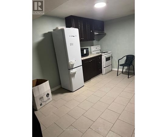 A kitchen with a white refrigerator, a white stove, and a black chair.