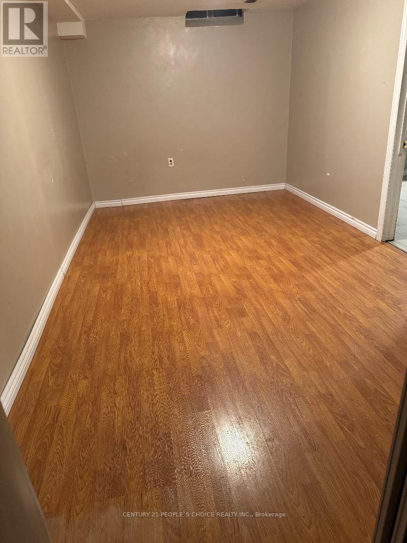 A room with wooden flooring and a realtor logo on the wall.
