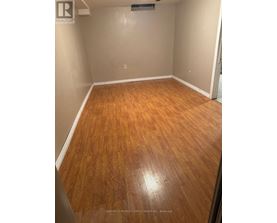 A room with wooden flooring and a realtor logo on the wall.